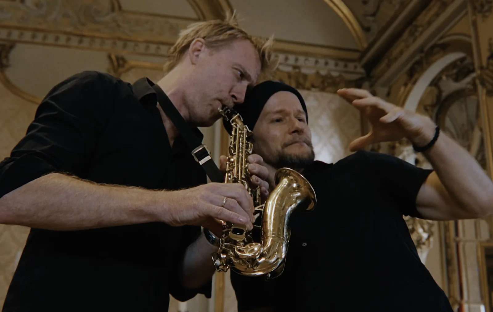 Kyrre Texnæs on stage together with a musician playing saxophone, in a gilded room