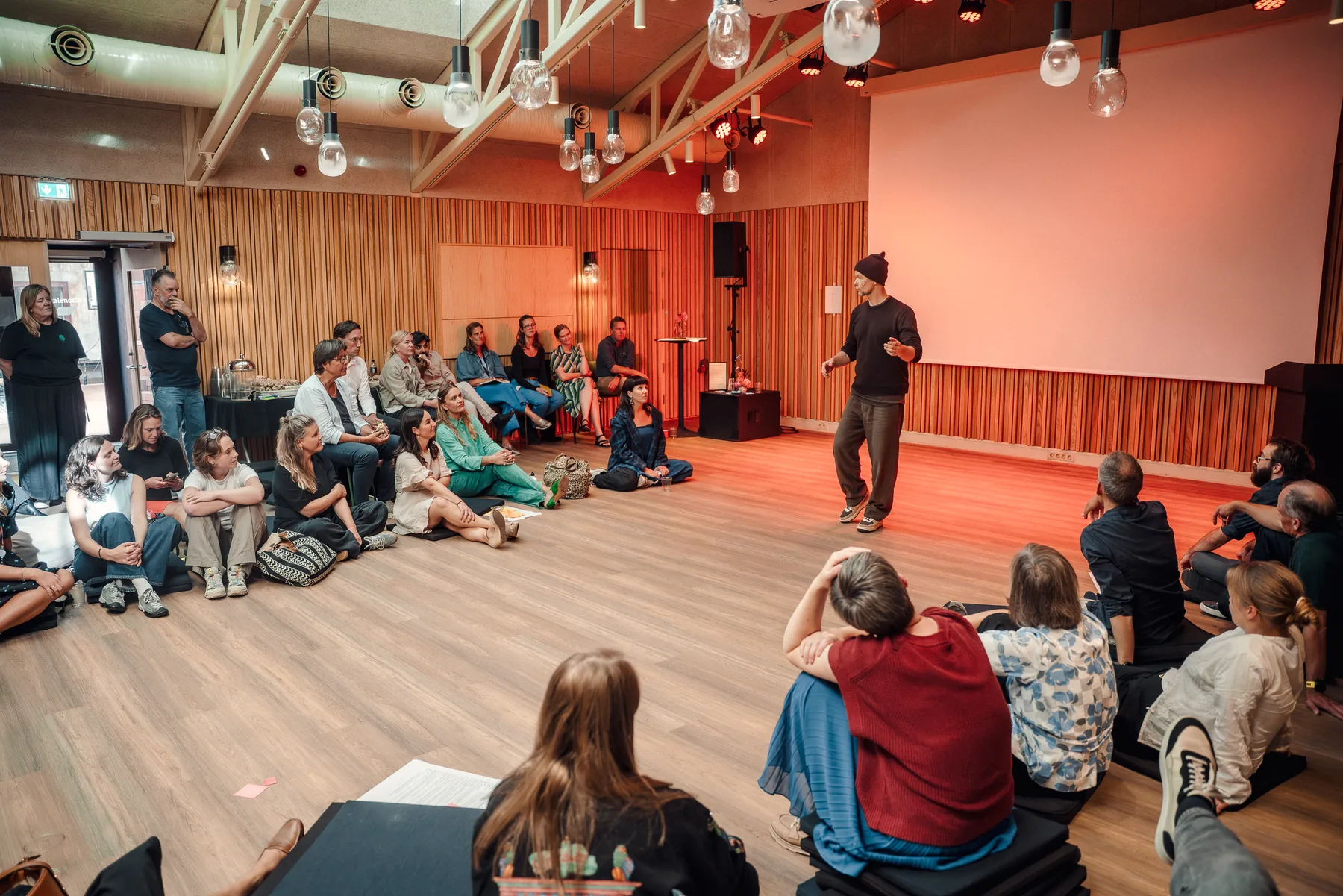 Et fullt rom på Sentralen, folk sitter på gulvet