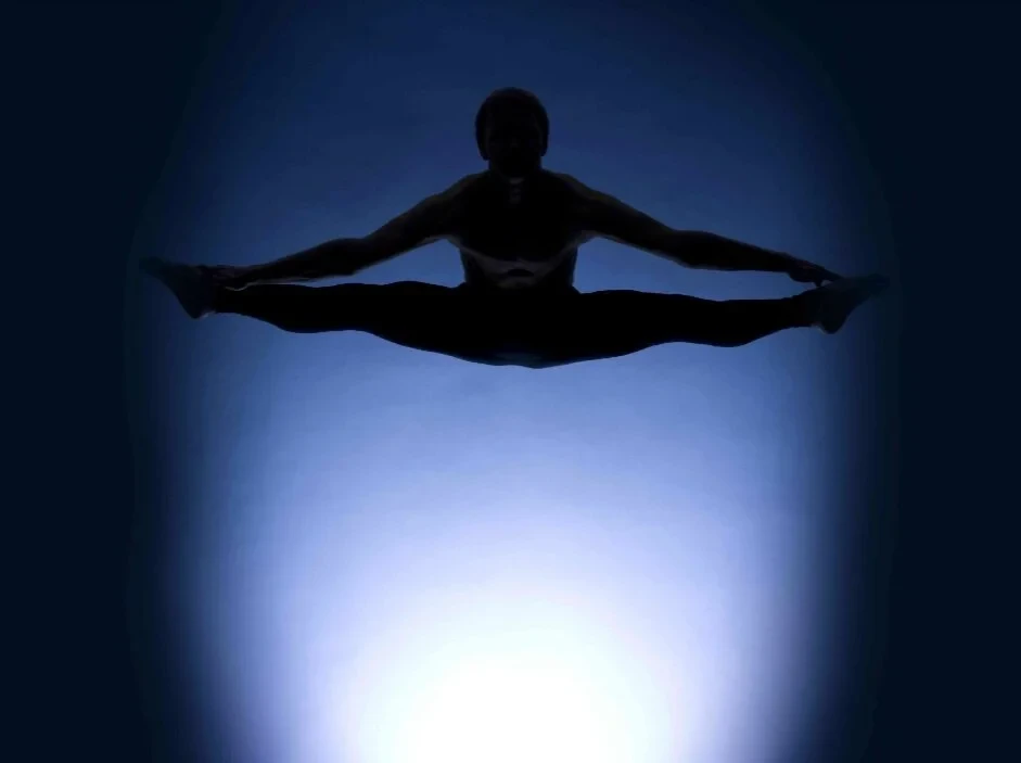 Kyrre Texnæs in a symmetrical mid-air split, silhouetted against light